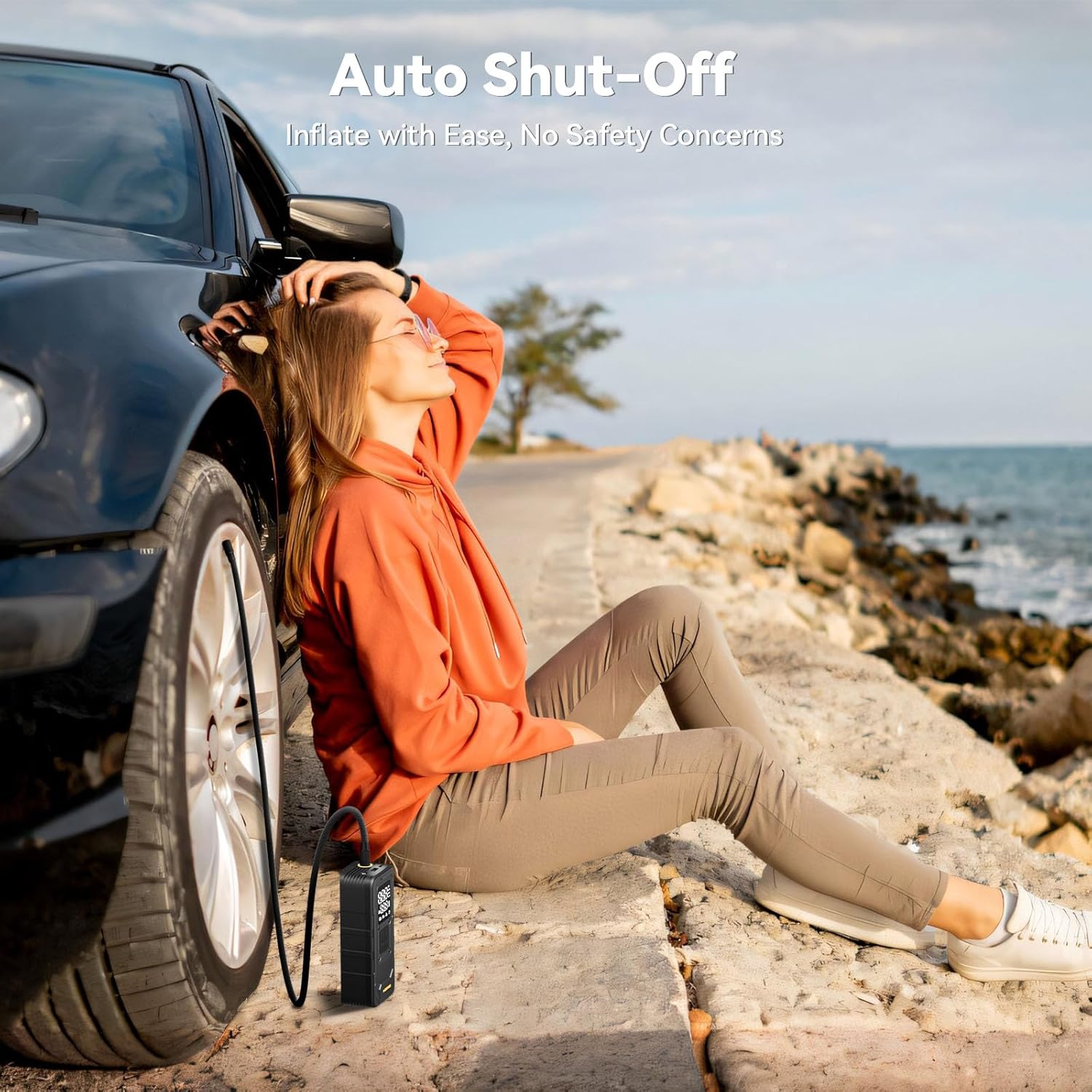 MODARI Tire Inflator Portable Air Compressor in use - Woman relaxing by a car tire with auto shut-off feature, showcasing easy, safe inflation by the seaside, from MODARI.